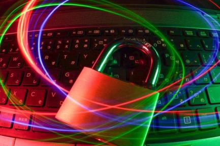 A laptop with a padlock laying on top of it. Red, green, and blue lines swirl over the lock. 